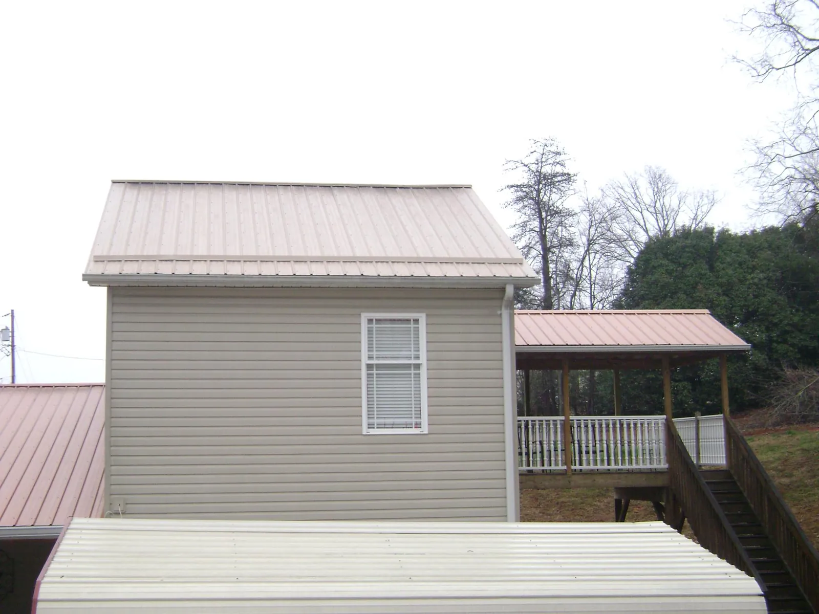 Tan metal roofs on a two story addition and attached porch, from a Roof Replacement job in Danville
